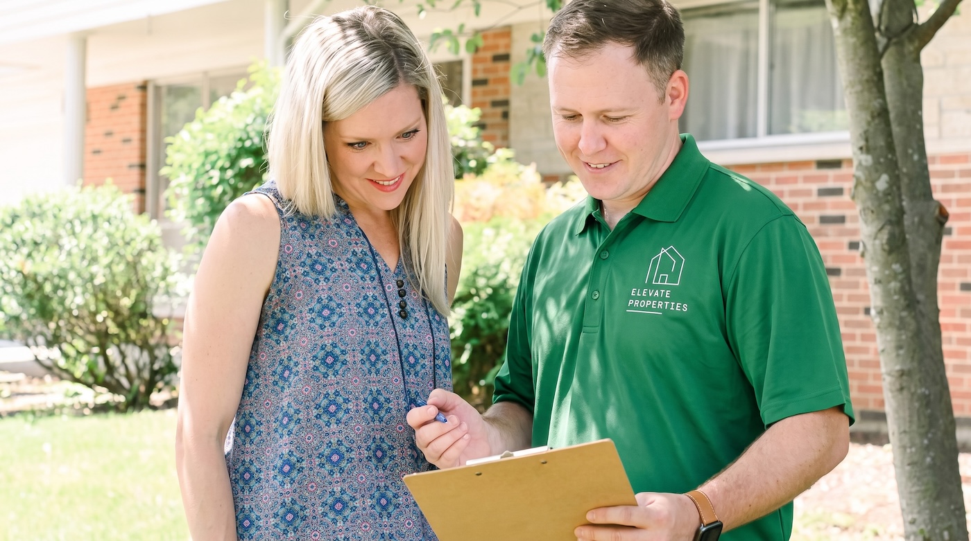 Two Elevate Properties people going through a homeowner's details together outside a house